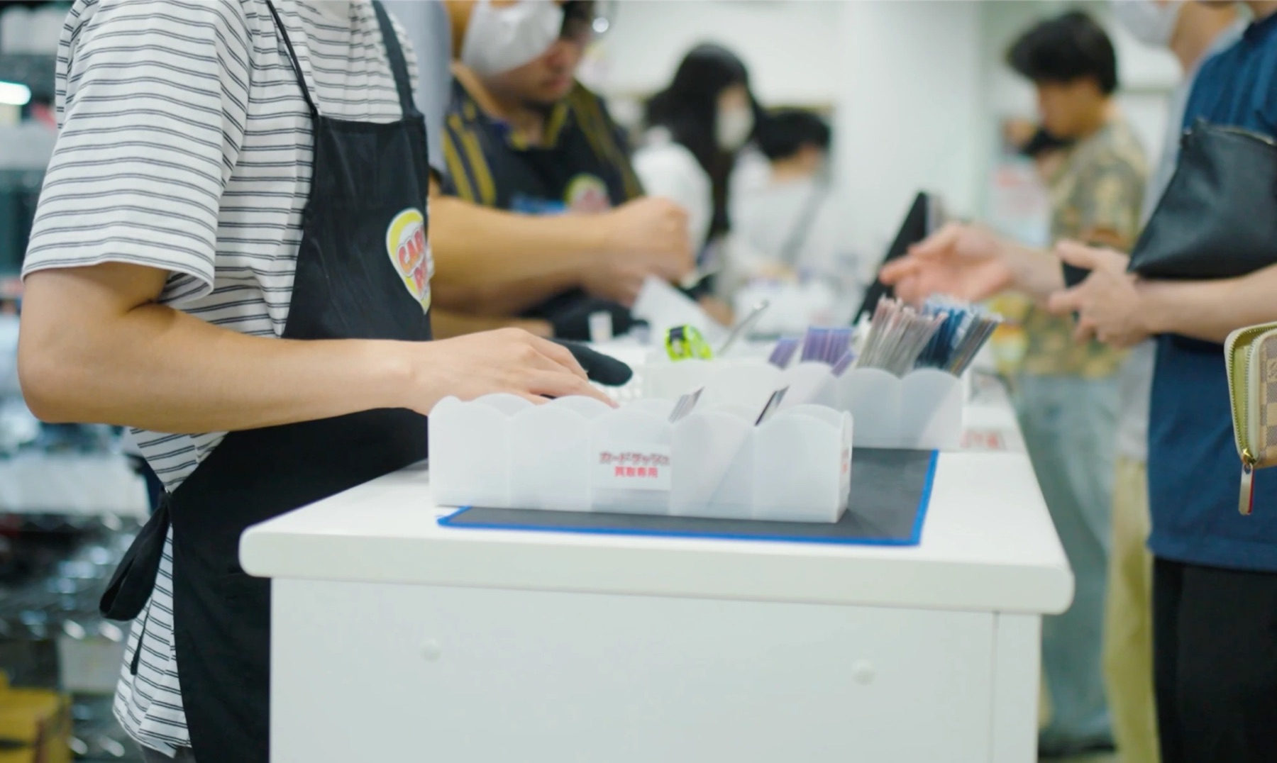 買取専用トレーでカードを確認する買取スタッフ